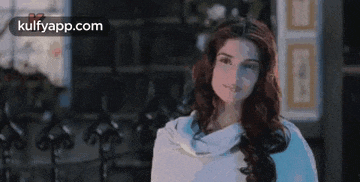 a woman with long red hair is wearing a white sweater and a white scarf .