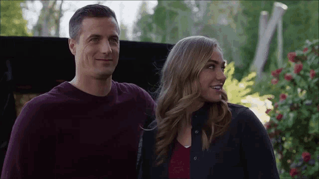 a man and a woman are standing next to each other smiling