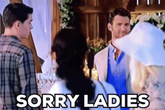 a man and a woman are standing next to each other in a room with the words `` sorry ladies '' written above them .