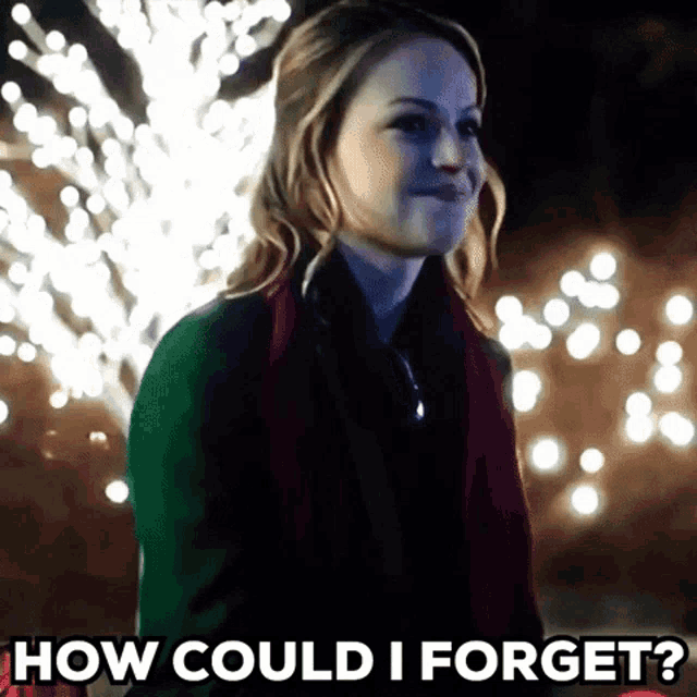 a woman is standing in front of a christmas tree and asking how could i forget ?