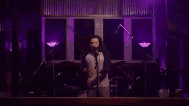 a man is singing into a microphone with his arms outstretched .