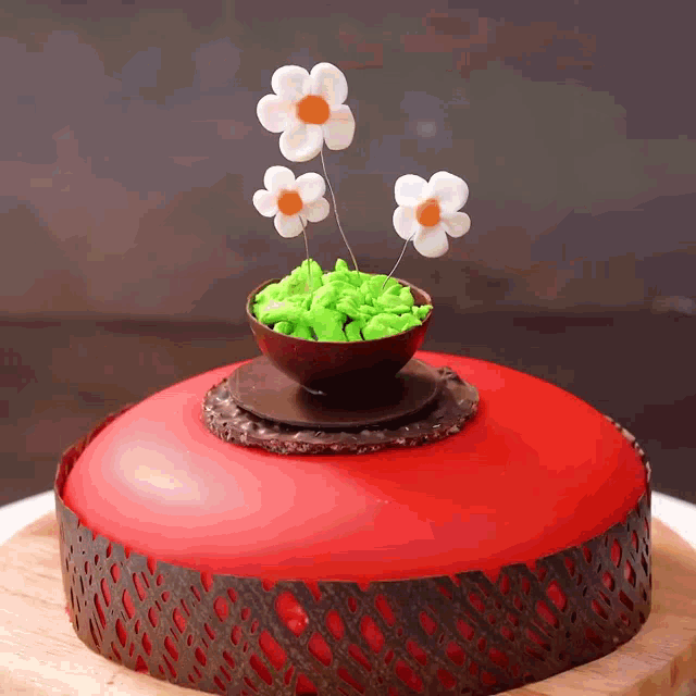 a red cake with flowers in a bowl on top of it