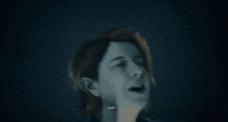 a woman is covering her mouth with her hands in a dark room in a blurry photo .