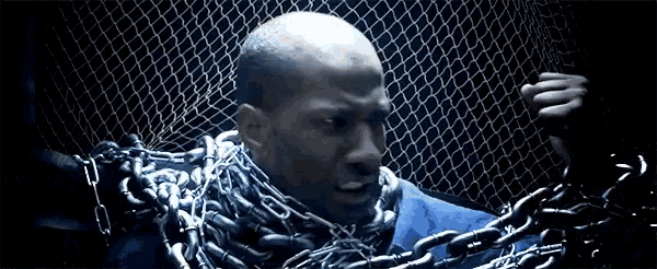 a man wearing chains around his neck is standing in front of a chain link fence