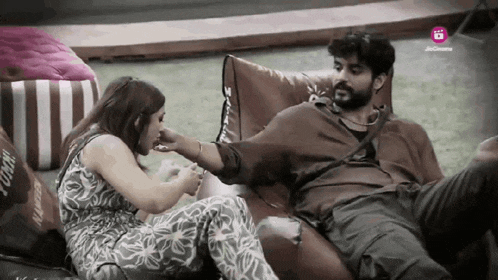 a man and a woman are sitting on a couch and the man is feeding the woman a piece of food
