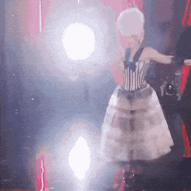 a woman in a corset and white dress is standing in front of a red curtain