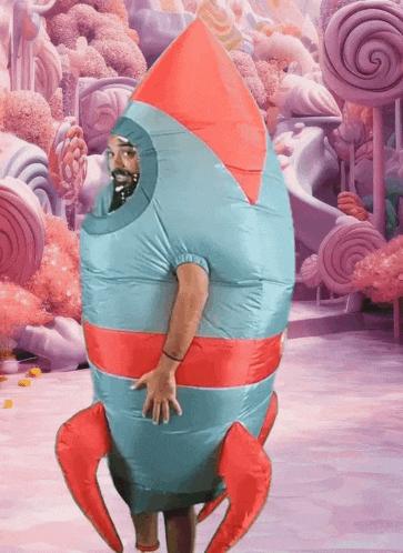 a man in an inflatable rocket costume stands in front of candy