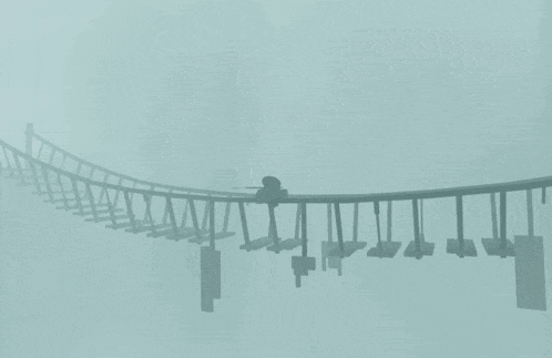 a silhouette of a person standing on a bridge in a foggy day