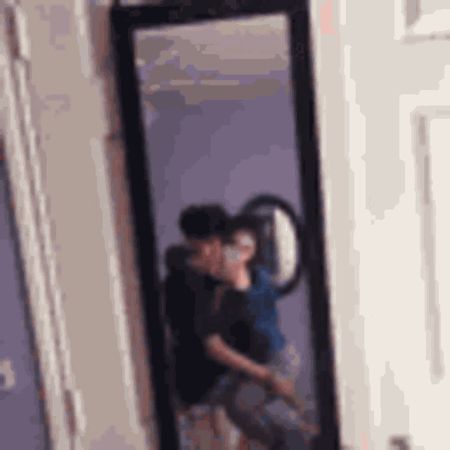 a man is taking a picture of himself and another man in a mirror .