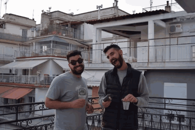 two men standing on a balcony with one wearing a shirt that says ' abercrombie & fitch ' on the front