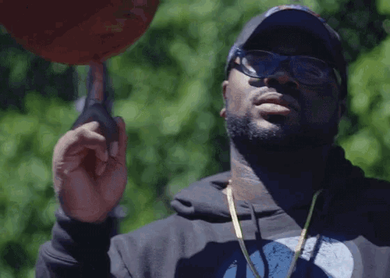 a man wearing a hat and sunglasses holds a basketball in his hand
