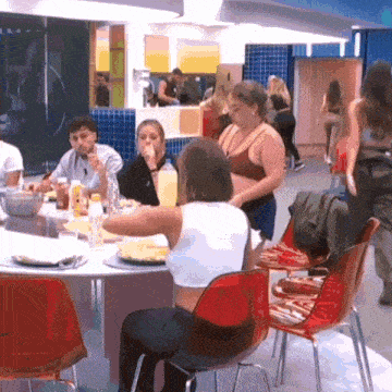 a group of people are sitting around a table with plates of food