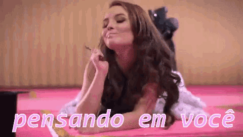 a woman is laying on a bed with the words " pensando em voce " written above her