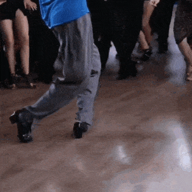 a man in a blue shirt is dancing with a group of people