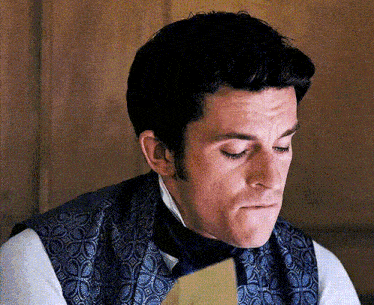 a man in a blue vest and tie is looking down