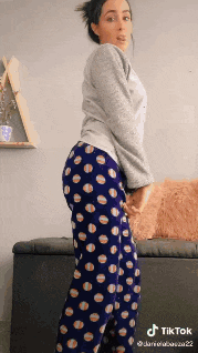 a woman in polka dot pajamas is standing in front of a couch ..