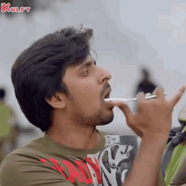 a man is holding a toothbrush in his mouth .