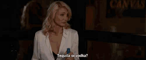 a woman is holding a bottle of tequila and a bottle of vodka in her hand .