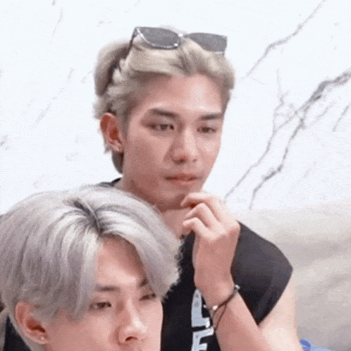 a man with sunglasses on his head is sitting next to another man with gray hair .