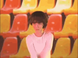 a woman is standing in front of a row of orange and yellow chairs .