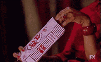a woman in a red dress is holding a box of popcorn