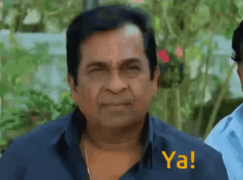 a man in a blue shirt is making a funny face with the words ya written on the bottom .