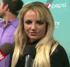 a woman is talking into a microphone in front of a pepsi ad