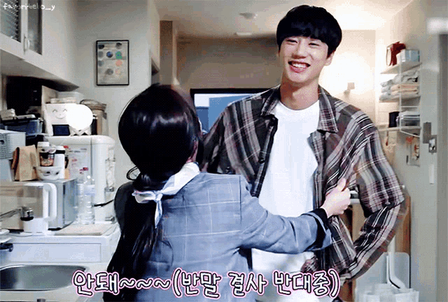 a woman is hugging a man in a plaid shirt in a kitchen with korean writing on the bottom