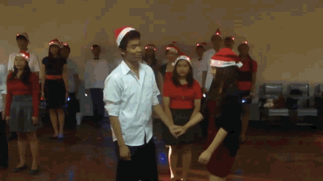 a group of people wearing santa hats are dancing in a room