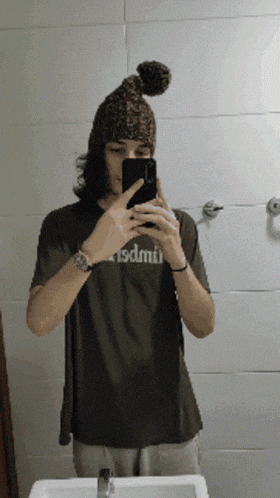 a man taking a selfie in front of a mirror with a shirt that says sdmiu