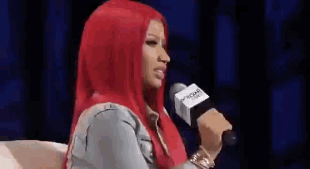 a woman with red hair is sitting in front of a microphone and talking into it .