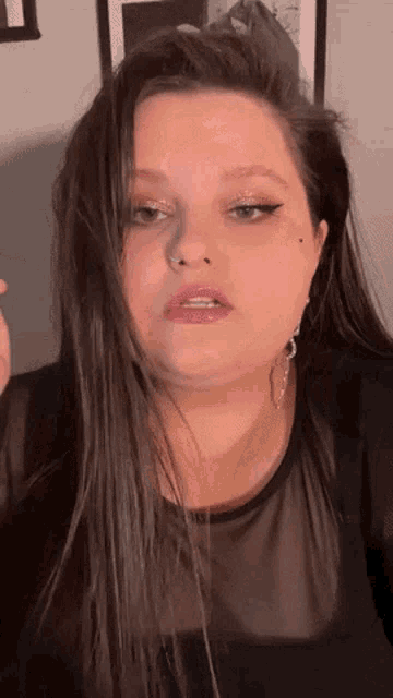 a woman with long hair is wearing a black shirt and earrings