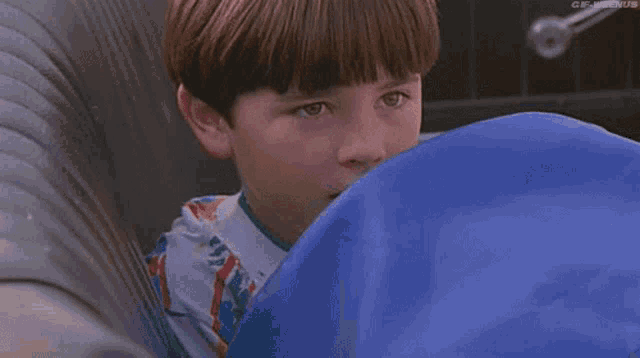 a young boy is sitting in a car with a blue balloon in his hand .