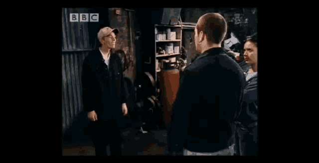 a group of people are standing in a garage with a sign that says bbc