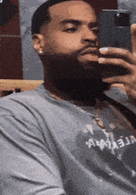 a man with a beard is taking a picture of himself with his phone