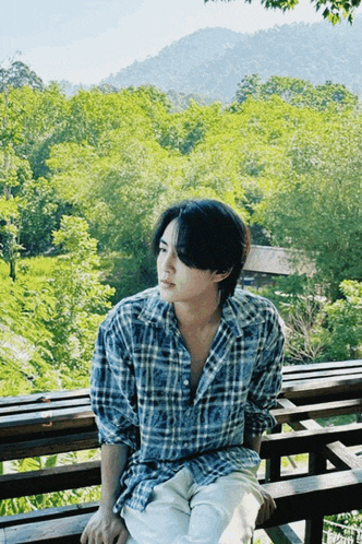 a man in a plaid shirt is sitting on a wooden bench