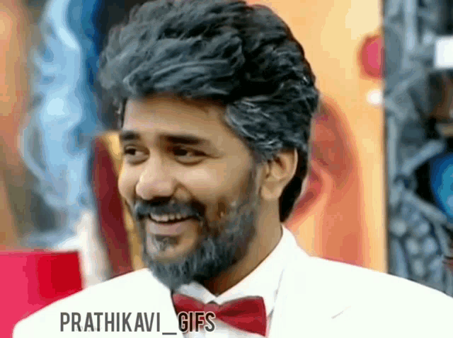 a man with a beard and a bow tie is smiling .