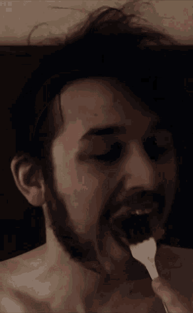 a man with a beard is brushing his teeth with a spoon
