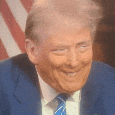 a man in a suit and tie is smiling with his eyes closed