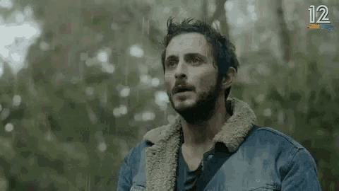 a man with a beard and a furry jacket is screaming in the woods .