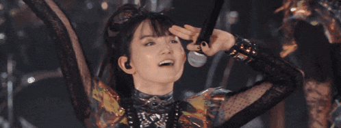 a woman is singing into a microphone with her arms in the air