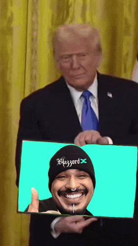 a man in a suit and tie is holding a picture of a man wearing a beanie that says wizzard on it