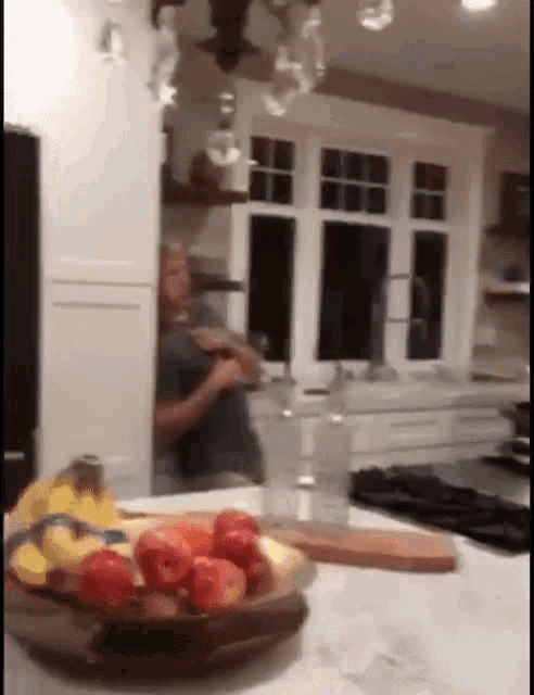 a bowl of fruit sits on a kitchen counter