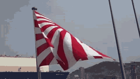 a red white and blue flag is flying in front of a large ship