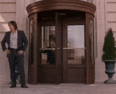 a man in a suit stands in front of a round door that is open