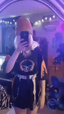 a girl is taking a selfie in front of a mirror while wearing a harley davidson shirt .