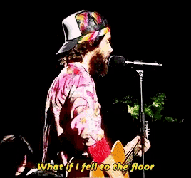 a man singing into a microphone while holding a guitar and the words what if i fell to the floor