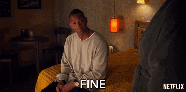 a man is sitting on a bed and the word fine is on the screen