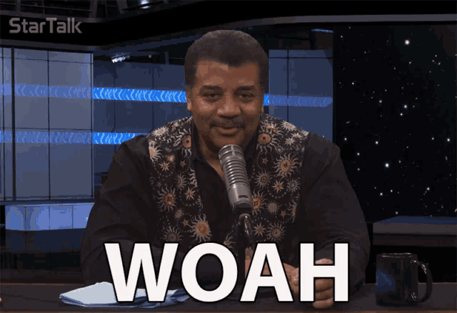 a man sitting in front of a microphone with the word woah on the screen