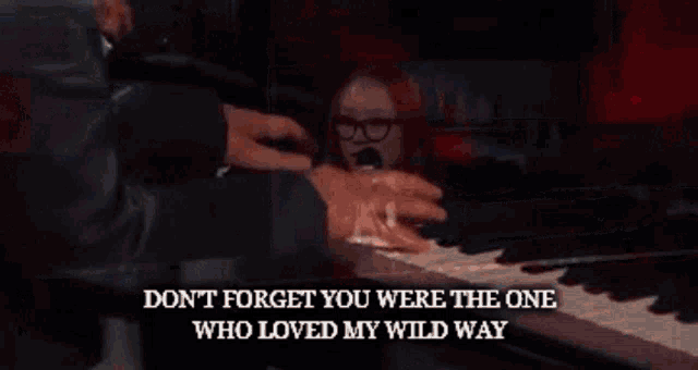 a woman singing into a microphone with the words " don t forget you were the one who loved my wild way " behind her